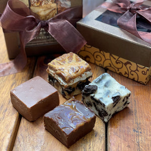 Four squares of gourmet fudge in front of gift box